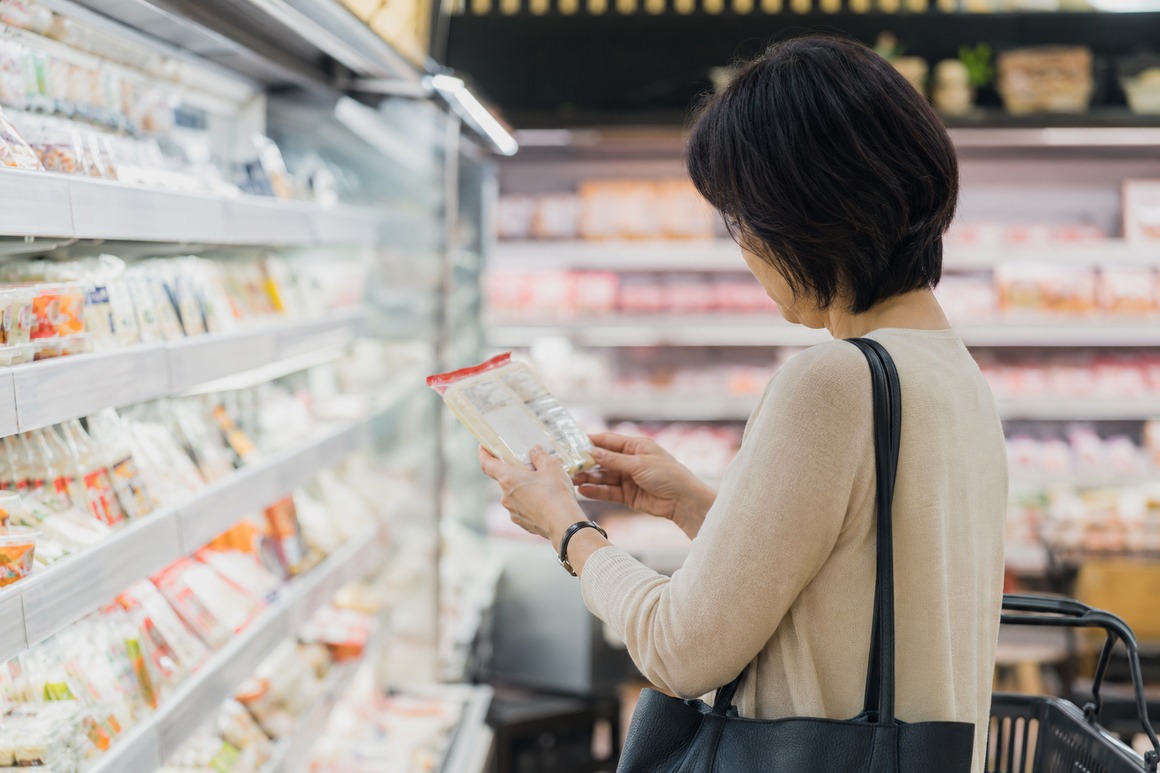 スーパーで食品の原材料表示を確認する女性